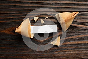 Tasty fortune cookie and paper with prediction on wooden table, flat lay. Space for text