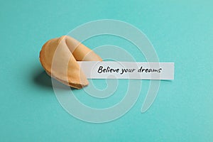 Tasty fortune cookie with prediction Believe your dreams on cyan background