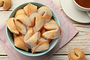 Tasty fortune cookies with predictions on white wooden table, flat lay