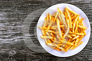 Tasty french fries on plate, on wooden table background