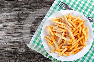 Tasty french fries on plate, on wooden table background