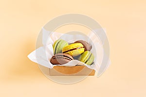 Tasty french macarons in a box on a peach pastel background