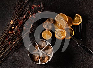 Tasty fresh baked sweets on dark background with oranges and flowers