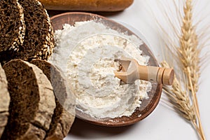 Tasty fresh black and white bread with wheat and flour on a white background