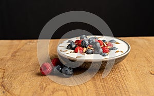 Tasty fresh blueberry raspberries  yoghurt shake dessert in ceramic bowl standing on black dark table background