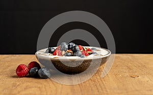 Tasty fresh blueberry raspberries  yoghurt shake dessert in ceramic bowl standing on black dark table background