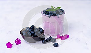 Tasty fresh blueberry yoghurt shake dessert in glass standing on white table background