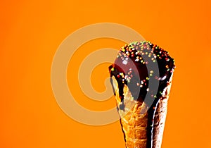 Tasty fresh cold ice cream with chocolate topping at orange background