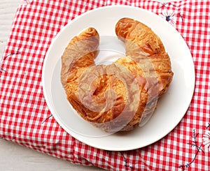 tasty Fresh crispy croissants arranged in white plate on cloth . Flat lay composition food photography.
