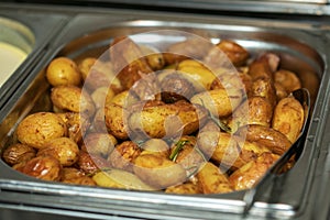 Tasty fresh homemade baked potatoes served on a metal tray. With various herbs, butter, garlic and salt. Gray stone