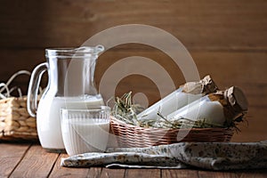 Tasty fresh milk in jug, bottles and glass on wooden table