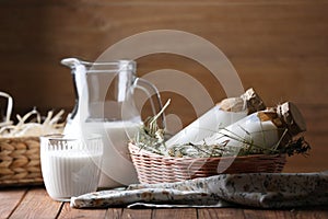 Tasty fresh milk in jug, bottles and glass on wooden table