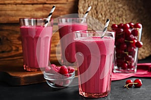 Tasty fresh milk shake with berries on black table. Space for text