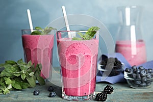 Tasty fresh milk shake with berries on light blue wooden table