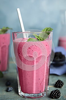 Tasty fresh milk shake with berries on light blue wooden table, closeup