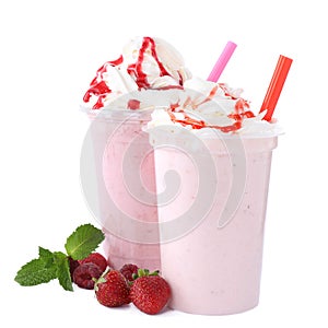 Tasty fresh milk shakes in plastic cups with ingredients on background