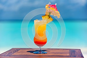 Tasty fresh pineapple cocktail on the wooden table at the beach with ocean