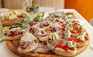 Tasty fresh sandwiches. Italian sandwiches with paprika, cheese, tomatoes and pesto sauce on a wooden plate.
