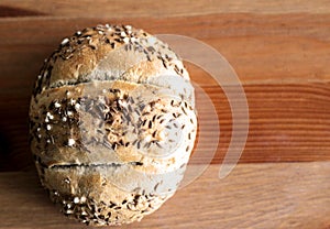 Tasty freshly baked butter kaiser roll with linseed and sunflower seeds. Top view, copy space, selective focus. Pastries