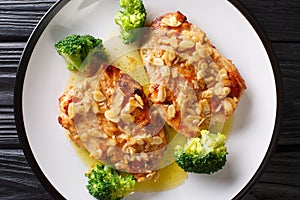 Tasty fried Amandine chicken fillet with almonds served with broccoli close-up on a plate. Horizontal top view