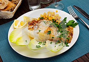 Tasty fried codfish served with endive, greens and corn
