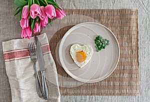 Tasty Fried Egg in the Shape of a Heart Served on a White Plate with Green Peas