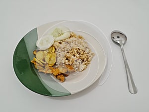 Tasty fried rice in a plate with a side dish of fried fish plus cucumber slices