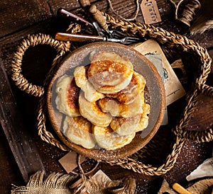 Tasty fried russian pancakes with powdered sugar on top in wooden bowl