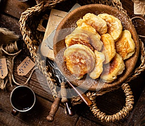 Tasty fried russian pancakes with powdered sugar on top in wooden bowl