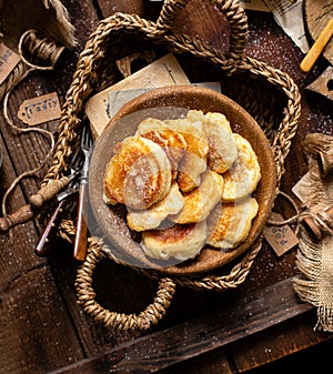 Tasty fried russian pancakes with powdered sugar on top in wooden bowl