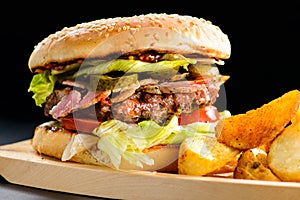 Tasty Gamburger with beef meat, tomato, pickes and potato wedges