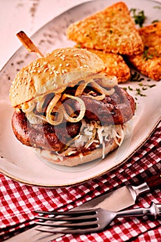 Tasty German bratwurst burger with onion rings