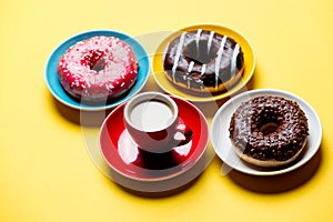 Tasty glazed donuts and cup of coffee on plates on the wonderful