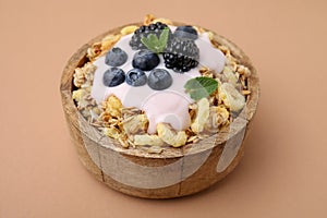 Tasty granola, yogurt and fresh berries in bowl on pale brown background, closeup. Healthy breakfast