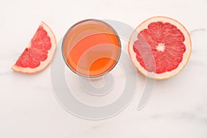 Tasty grapefruit juice in glass and slices of fresh fruit on white table, top view. Space for text