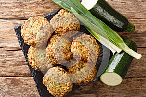 Tasty greek zucchini balls with feta cheese with ingredients close-up on a slate board. Horizontal top view