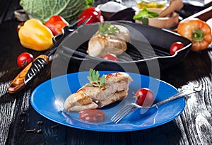 Tasty Grilled chicken fillet and bell pepper in a plate on the black table.