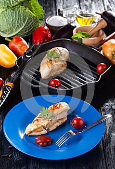 Tasty Grilled chicken fillet and bell pepper in a plate on the black table.