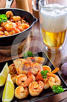 Tasty grilled shrimps with a glass of beer on wooden table