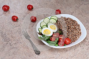 Tasty and healthy food from natural products. Salad of green vegetables, tomato and buckwheat in a white plate. Buckwheat with veg