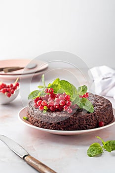 Tasty homemade chocolate cake brownie decorated with red currant berries and mint on white marble table, copy space