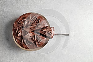 Tasty homemade chocolate cake and shovel with piece on table, top view.