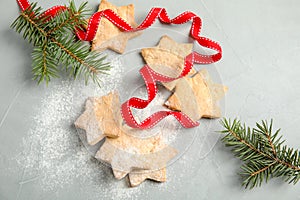 Tasty homemade Christmas cookies with ribbon fir tree twigs on table, top view