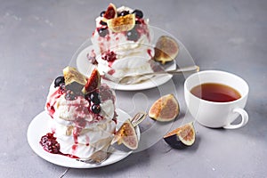 Tasty Homemade Dessert Mini Pavlova Cakes with Figs and Berry Homemade Pavlova Cake on Gray Background with Cup of Tea Horizontal