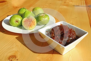 Tasty homemade fig jam with a plate of green fresh figs in the backdrop