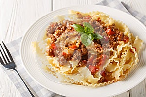 Tasty homemade Reginette Bolognese pasta closeup on the plate on the white table. Horizontal