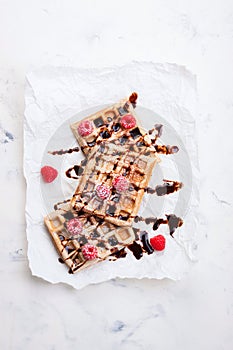 Tasty homemade waffles with raspberries and chocolate sauce ready for breakfast