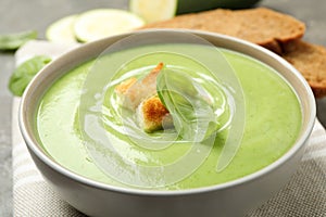 Tasty homemade zucchini cream soup in bowl on table