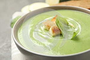 Tasty homemade zucchini cream soup in bowl on table, closeup