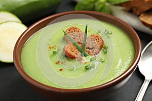 Tasty homemade zucchini cream soup in bowl on table, closeup